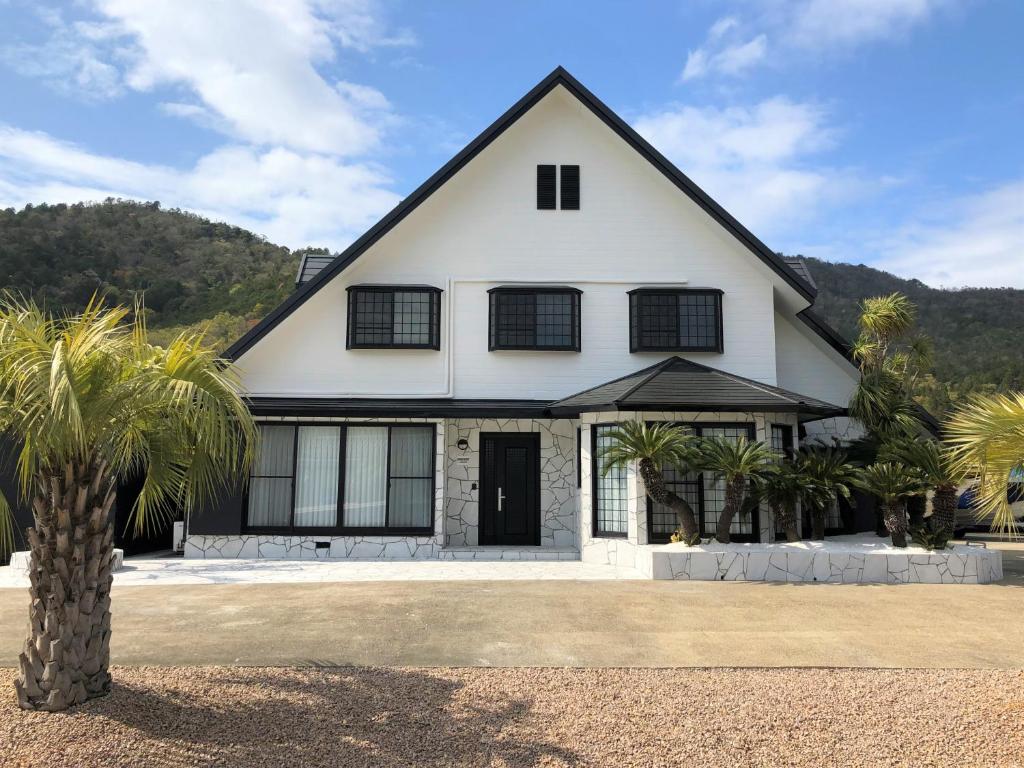 a white house with palm trees in front of it at BIWAKO RESORT Second House in Omihachiman