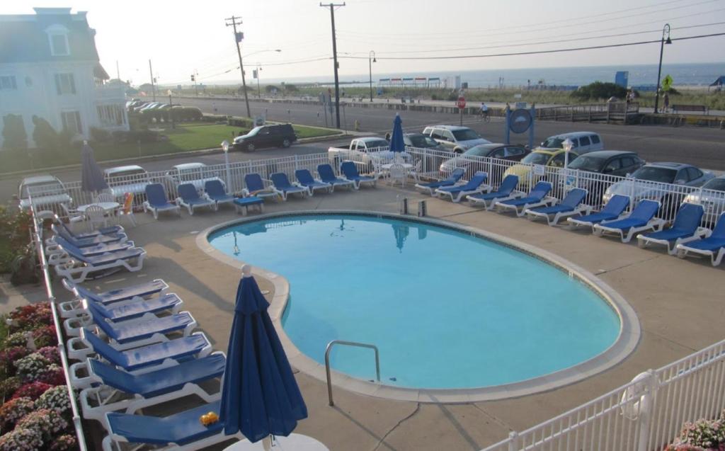a swimming pool with lounge chairs and a poolvisorangering at Colton Court Motor Inn in Cape May