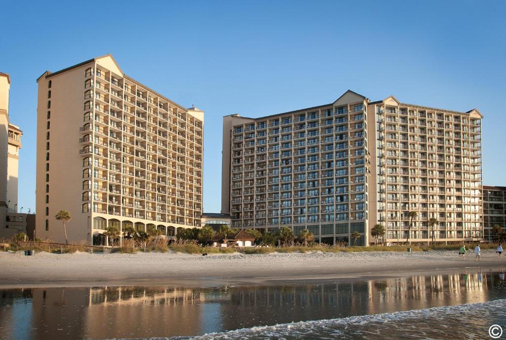 dos edificios altos junto a una playa con un edificio en Beach Cove Resort en Myrtle Beach