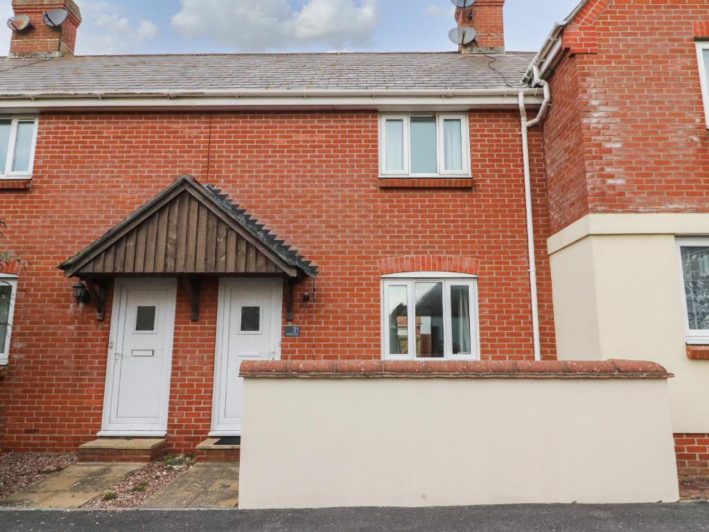 a red brick house with a white garage at Buttercups in Bridport