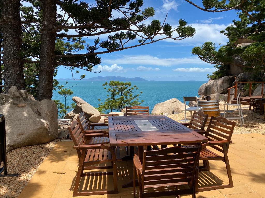 een houten tafel en stoelen met uitzicht op de oceaan bij The Boulders - Oceanfront Couple's Retreat with private pool near ferry in Nelly Bay