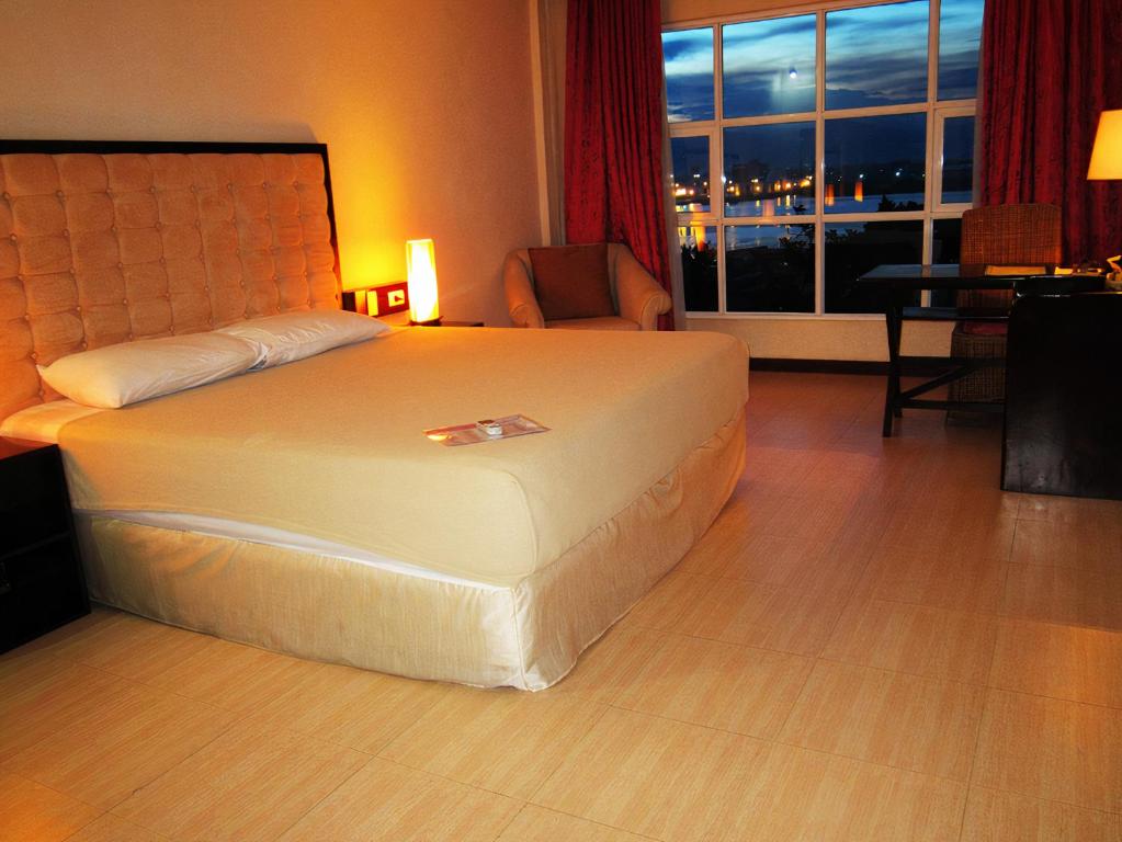 um quarto de hotel com uma cama e uma janela em Cebu Dulcinea Hotel and Suites-MACTAN AIRPORT HOTEL em Mactan