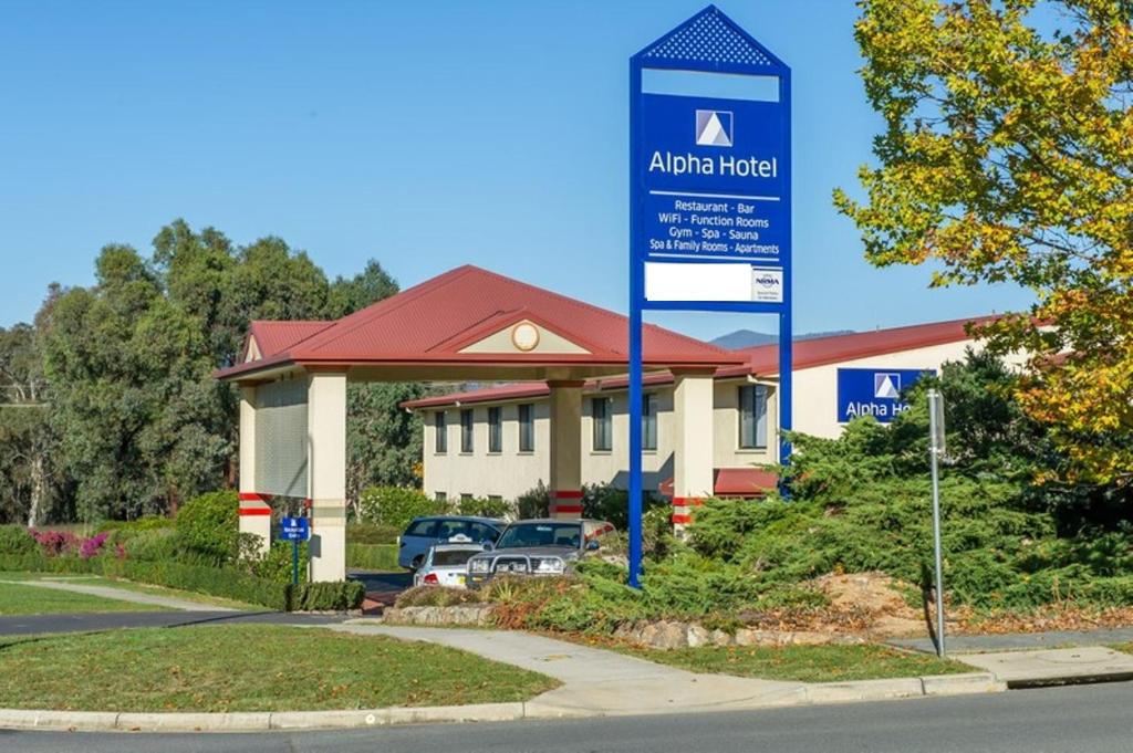 una señal de hotel frente a un edificio en Alpha Hotel Canberra, en Canberra