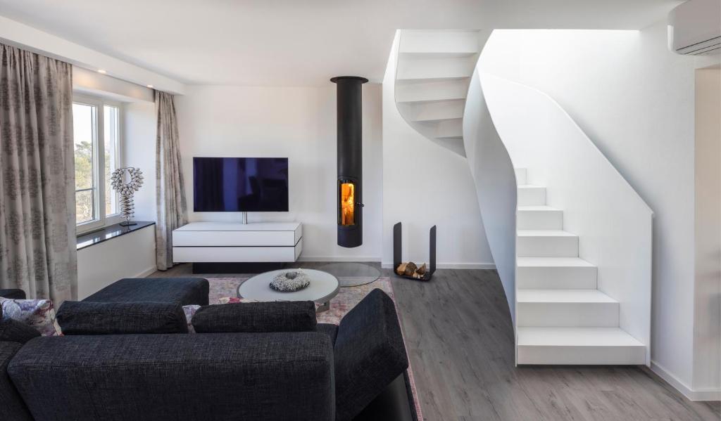 a living room with a couch and a staircase at Penthouse am Südstrand - Kamin, Dachterrasse mit Meerblick und Gasgrill, Luxus-Design-Apartment, 2 Minuten zum Strand, Klimaanlage in Binz