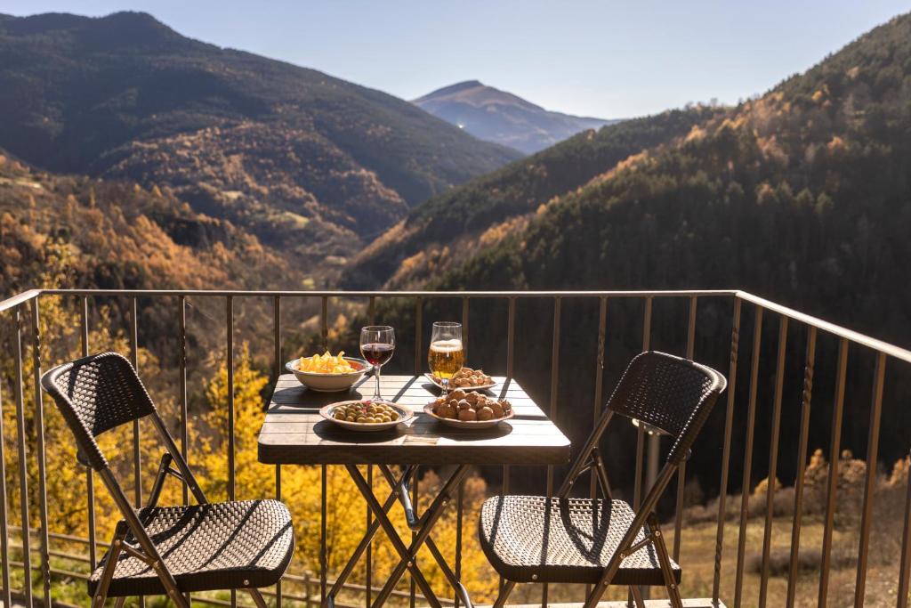 a table with food and glasses of wine on a balcony at Apartament SIAT in Queralbs