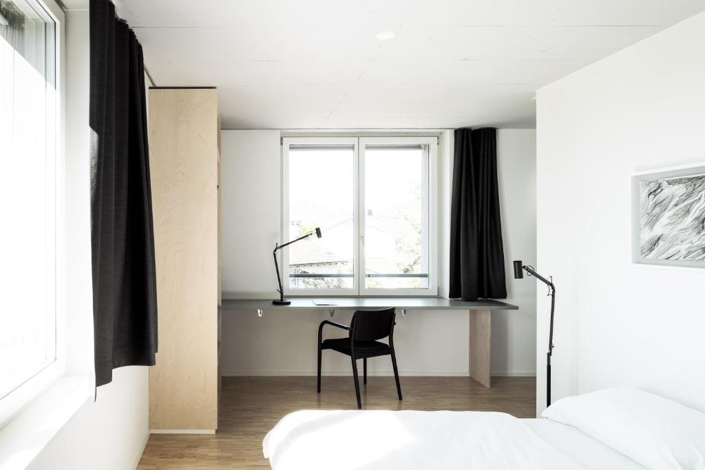 een slaapkamer met een stoel, een bed en een raam bij Guesthouse Meiersegg in Flawil