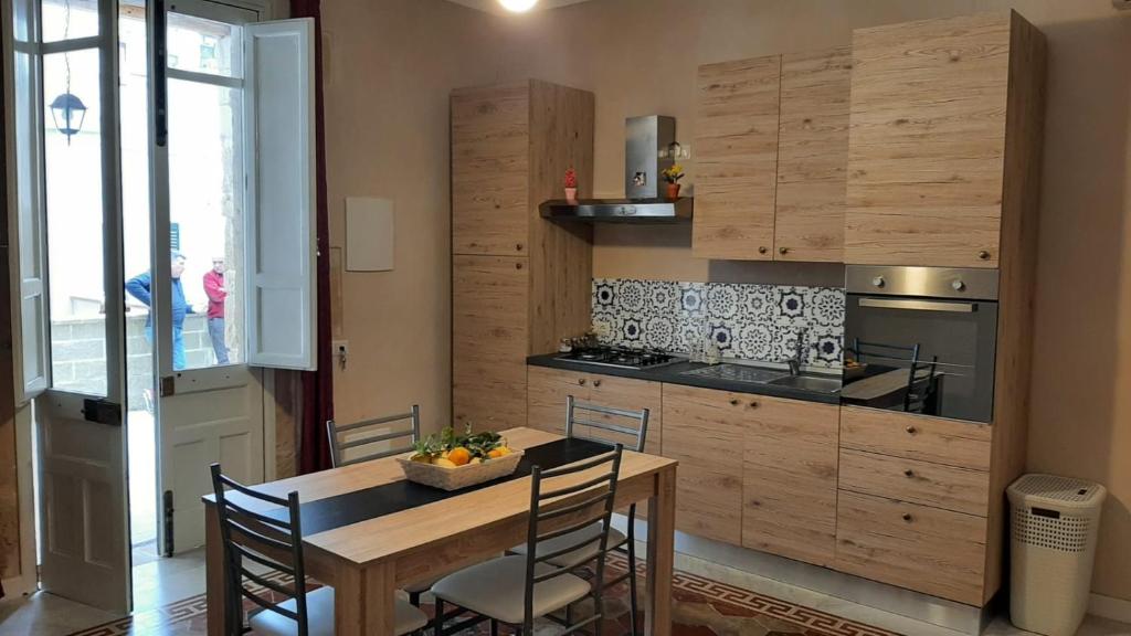 een keuken met een houten tafel en stoelen bij Flower house in Noto