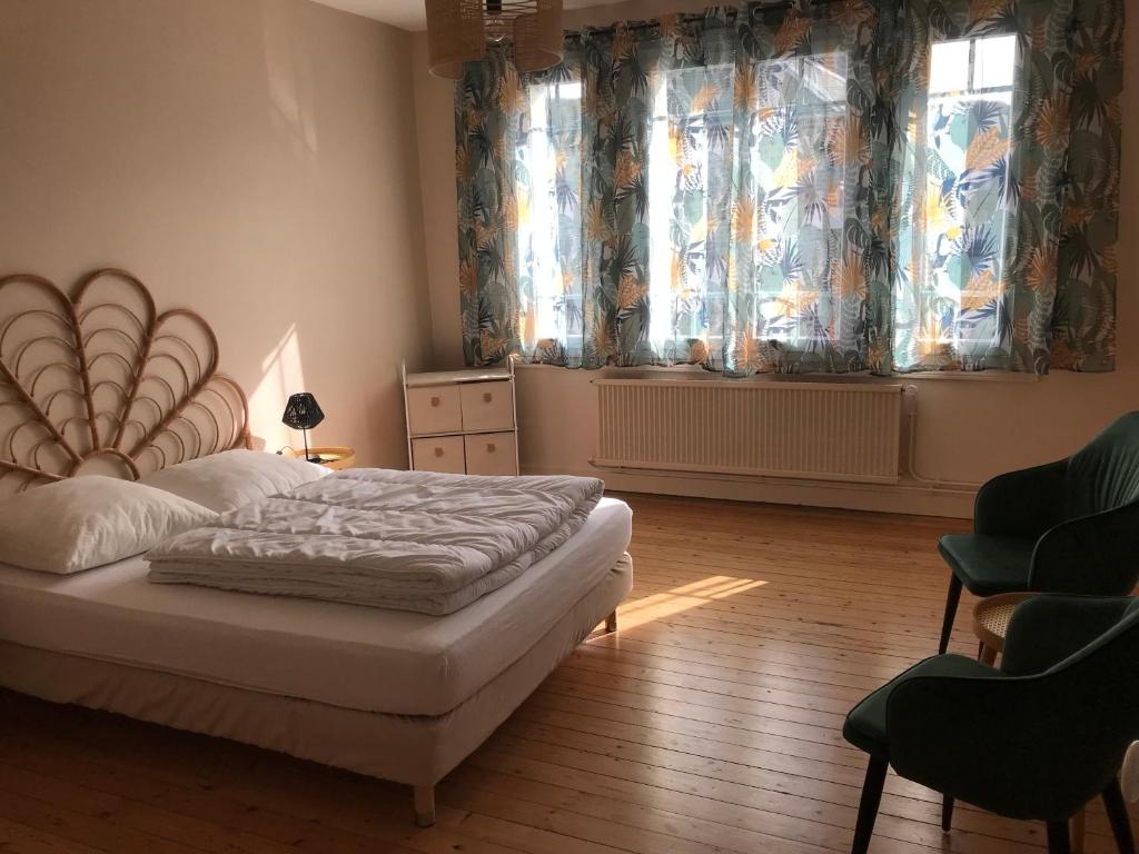 a bedroom with a bed and two windows with curtains at Les sources Yportaises in Yport