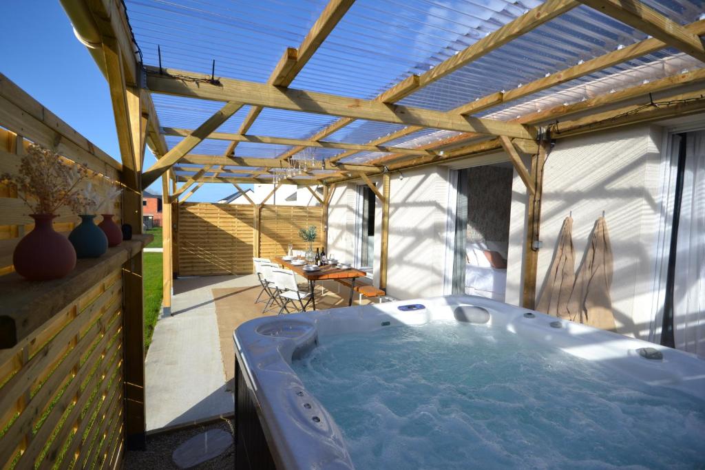 ein Whirlpool auf einer überdachten Terrasse in der Unterkunft La Bulle Emeraude, détente à deux, en famille ou entre amis in Plancoët