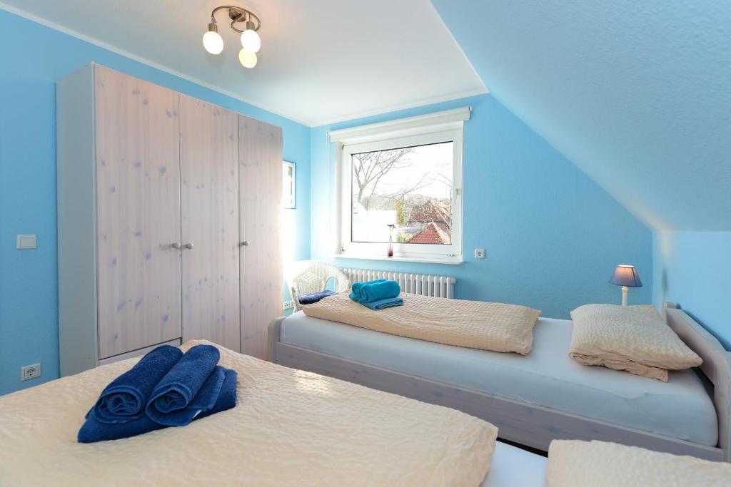 2 camas en una habitación con paredes azules y ventana en Fewo Halligweg 8 en Wyk auf Föhr