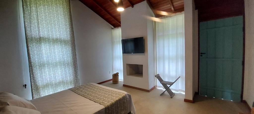 a bedroom with a bed and a chair and windows at Paiol Eco Suites in Paraty