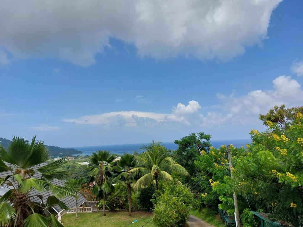 a view of the ocean from a resort with palm trees at Creole Cottage Apartment in Anse Royale