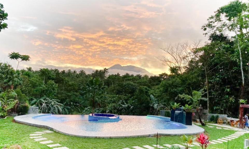 una piscina en un patio con una puesta de sol en el fondo en BALAI BANAHAW Vacation Farm and Private Resort en Lucban