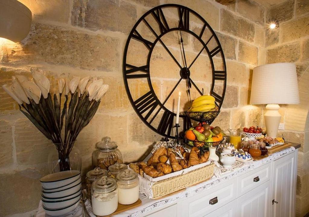 a large clock on a wall next to a table with food at Betty Cake B&B in Qala