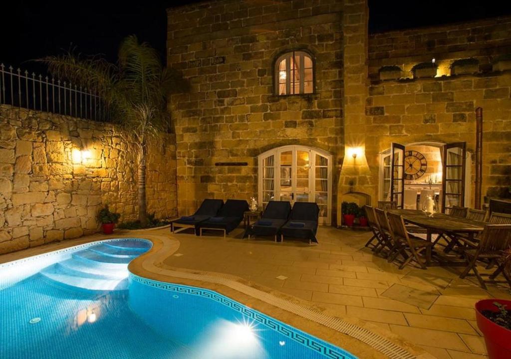 a swimming pool in front of a house at night at Betty Cake B&B in Qala