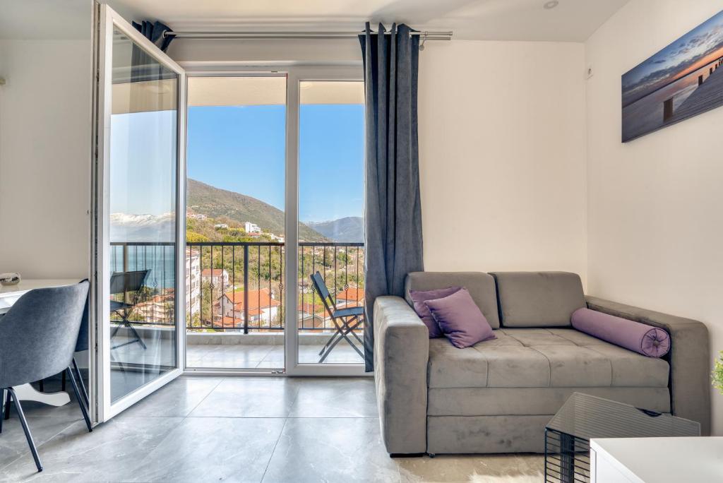 a living room with a couch and a balcony at Apartment La Perla in Đenovići
