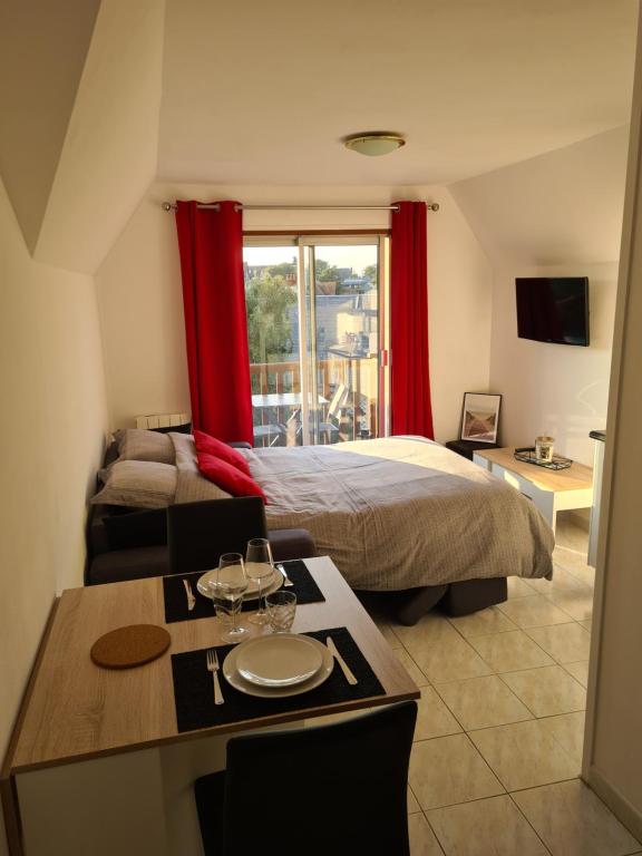 1 dormitorio con 1 cama y 1 mesa con comedor en Charmant studio proche de la mer, en Tourgéville