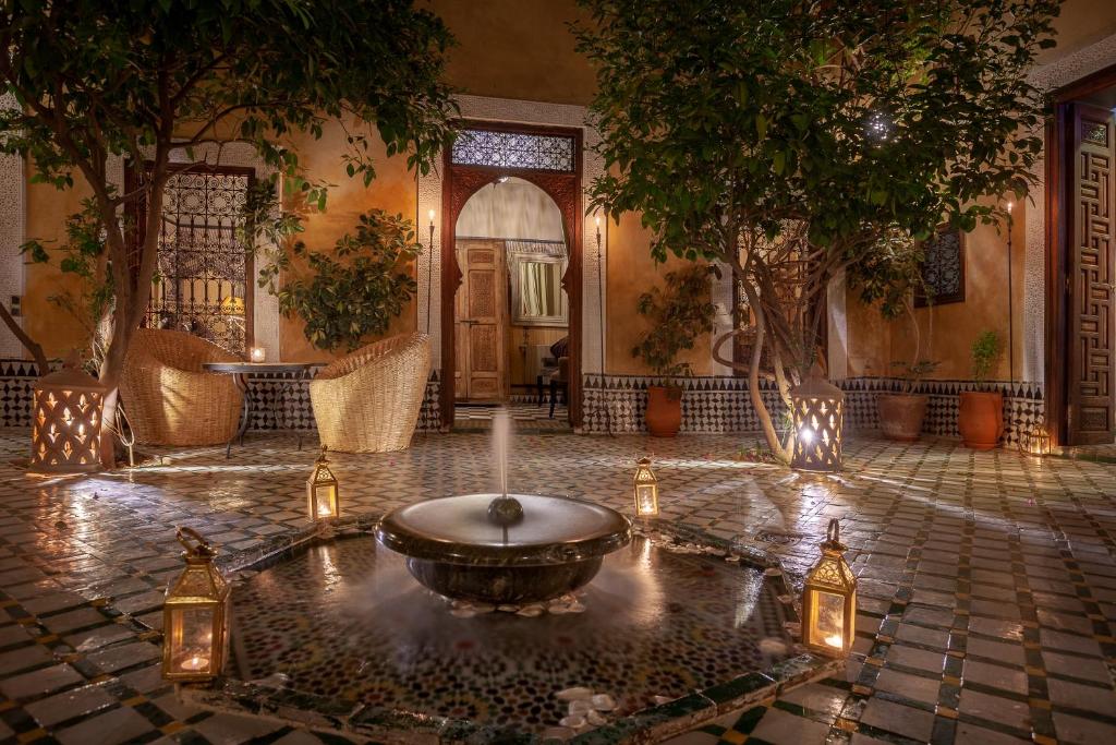 einen Innenhof mit einem Brunnen in einem Gebäude mit Lichtern in der Unterkunft Riad Bohémia in Marrakesch