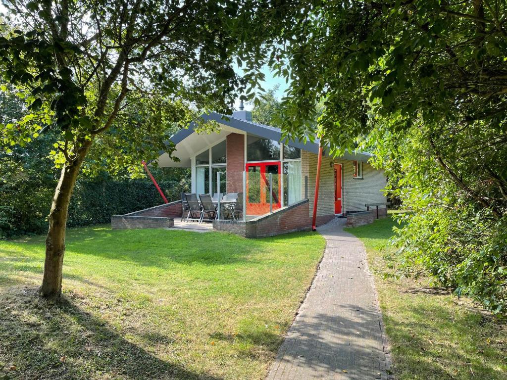 una casa con una puerta roja y una acera en Bungalows Dellewal en West-Terschelling
