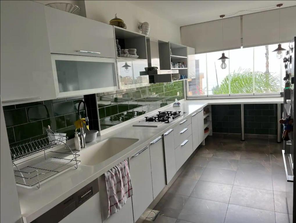 cocina con armarios blancos y ventana grande en Panoramic Sea View 2 Bedroom Apartment en Jbeil