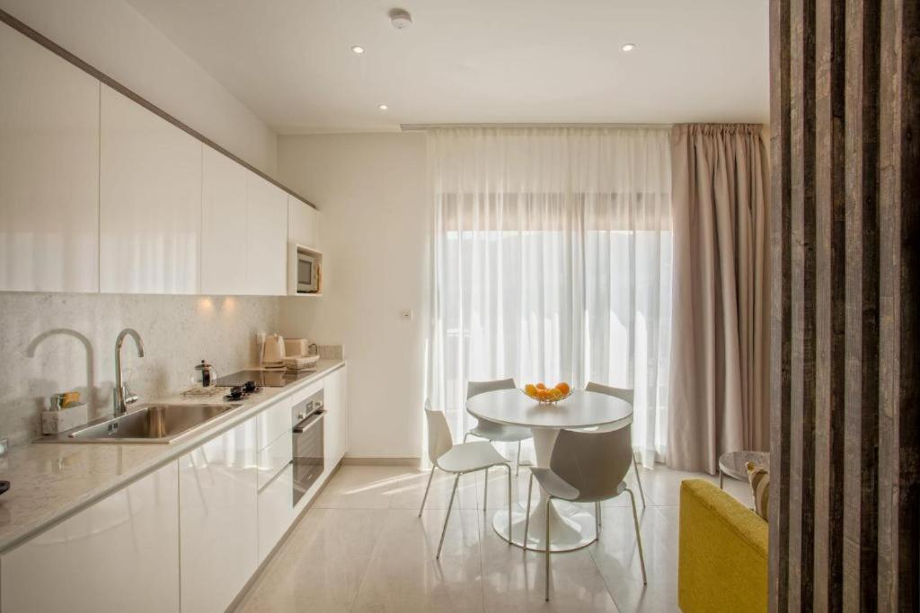 cocina blanca con mesa y fregadero en Appartement E RONDINELLE 2, en Belgodère