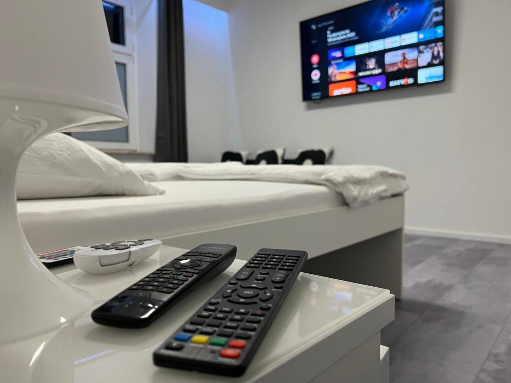 two remote controls sitting on a table next to a bed at Freshly renovated City Apartments Essen near Düsseldorf Airport in Essen