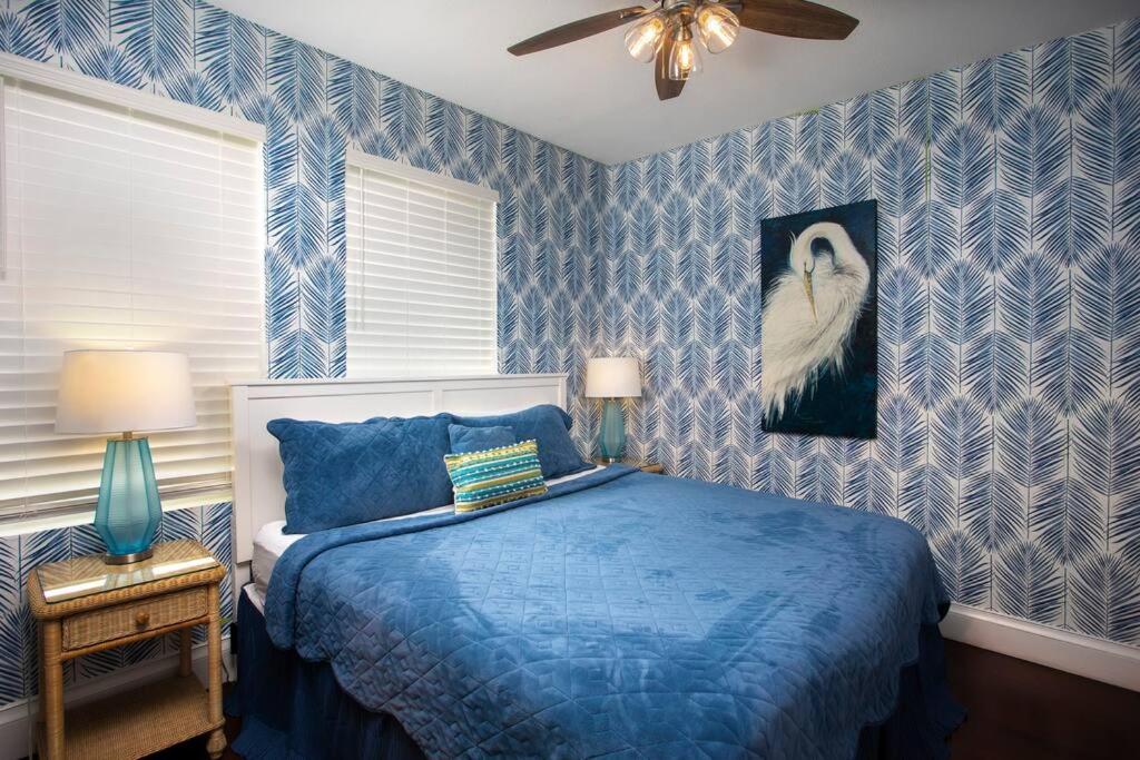 a blue bedroom with a bed and a painting of a bird at Duval Street Suite with pool in Key West