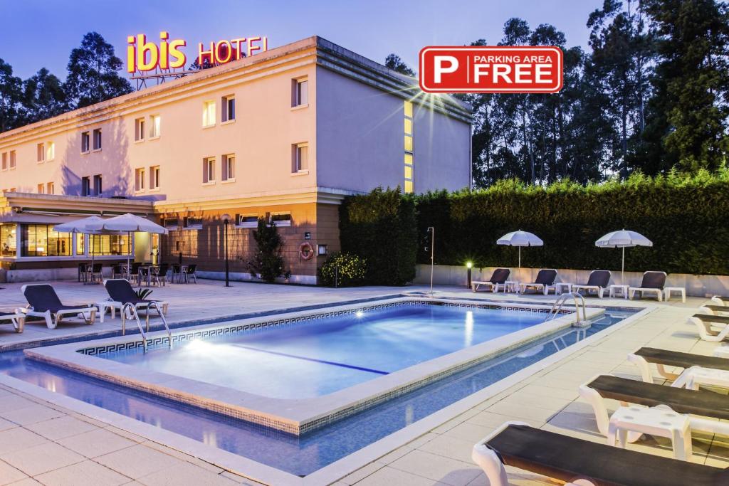uma piscina num hotel com cadeiras e guarda-sóis em Hotel ibis Porto Sul Europarque em Santa Maria da Feira