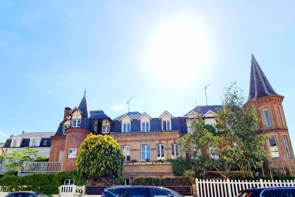 un gran edificio de ladrillo con techos puntiagudos y coches aparcados delante en Villa Bon Accueil en Deauville