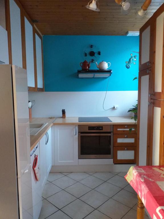 eine Küche mit weißen Schränken und einer blauen Wand in der Unterkunft Sympathique T3 près lac du Bourget in Serrières-en-Chautagne
