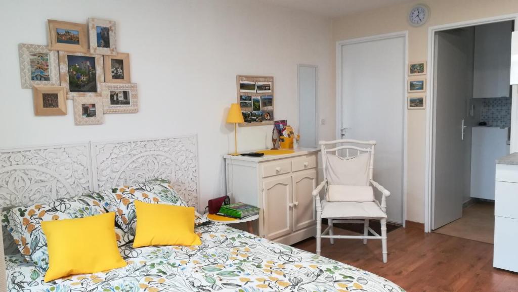 a bedroom with a bed with yellow pillows and a chair at Studio cosy Yssac-la-Tourette in Yssac-la-Tourette