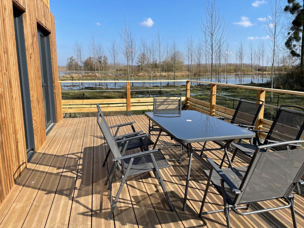 a patio with a table and chairs on a deck at Au fil de l’eau, gîte nature in Abbécourt