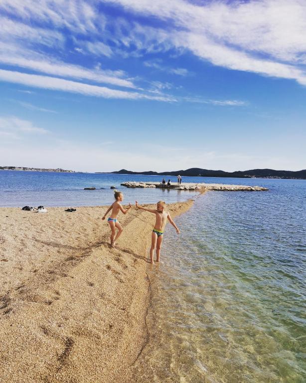 dwoje dzieci bawi się na plaży w obiekcie Apartment Gabrijel w mieście Sveti Filip i Jakov