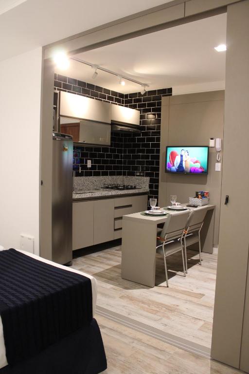 a kitchen and dining room with a table and a tv at Flats Monsenhor31 - Localizado no centro da cidade in Paulo Afonso