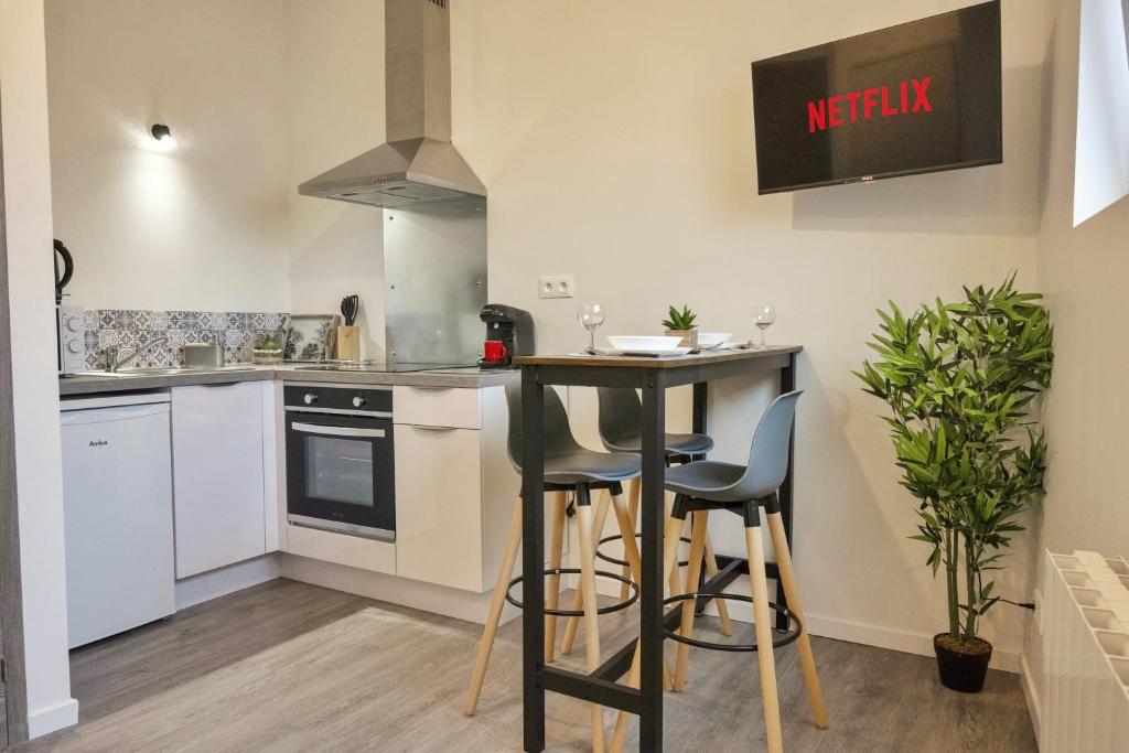 una cocina con mesa y taburetes. en ❂ Les Logis de la Trémoille ❂ Cozy ❂ Netflix ❂, en Thouars