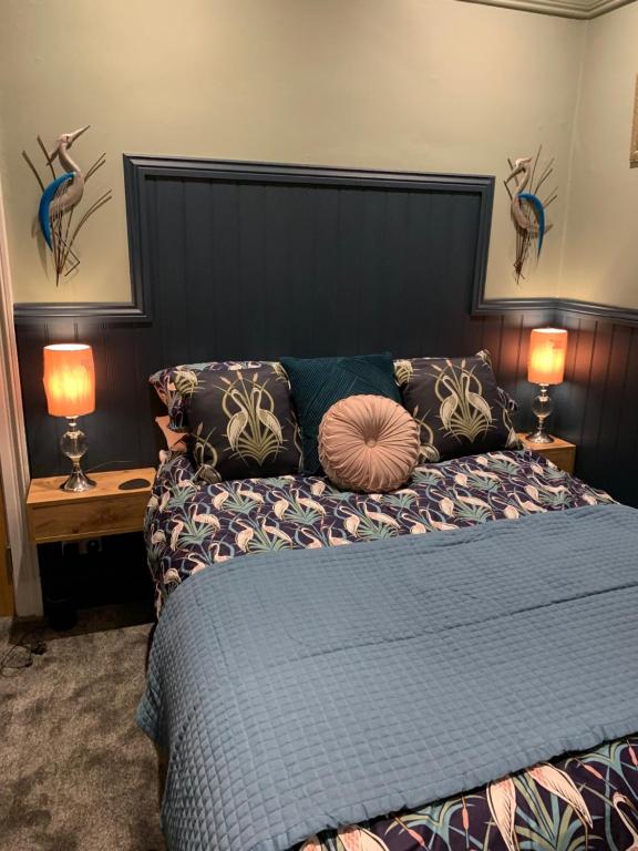 a bedroom with a blue bed with two lamps at CornerHouse Guesthouse in Penrith