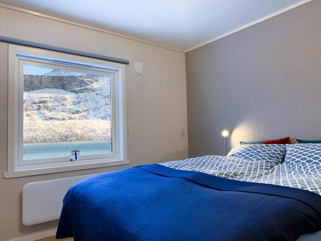 een slaapkamer met een blauw bed en een raam bij Segla Guesthouse - Lovely sea view in Fjordgård