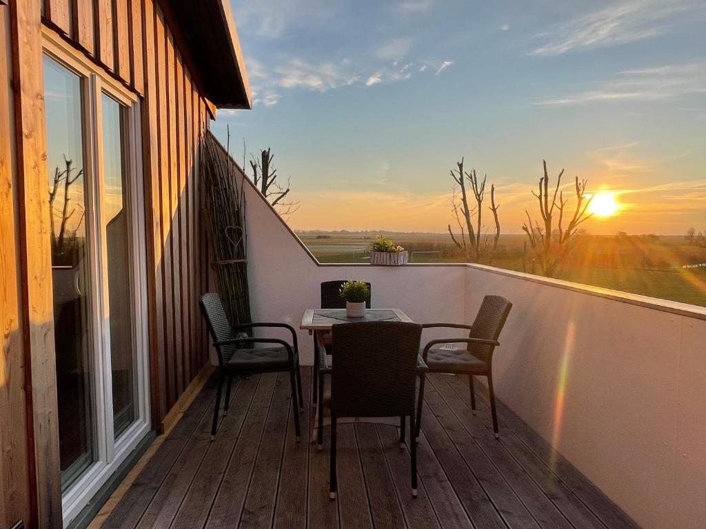 a balcony with a table and chairs and the sunset at Ferienwohnung Watt'n Ausblick in Simonsberg