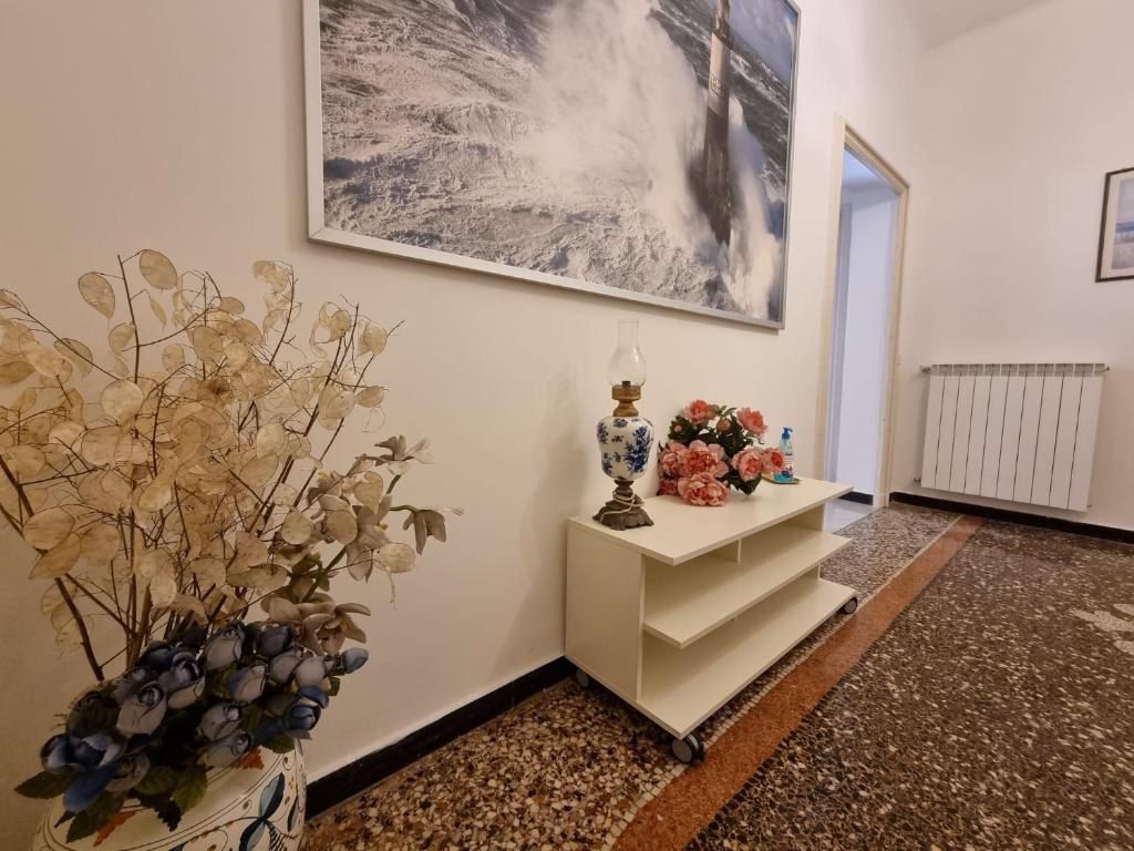 una habitación con una mesa con flores y una foto en la pared en WOW HOME 2 - 175 mq - posteggio privato - davanti porto traghetti - fino a 10 posti letto - balcone, en Génova