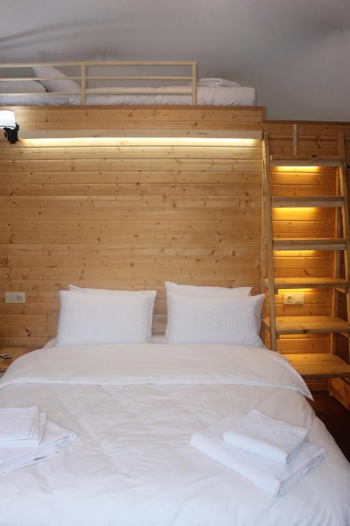 a bedroom with a large white bed with a wooden wall at Glamping Village in Sarpi