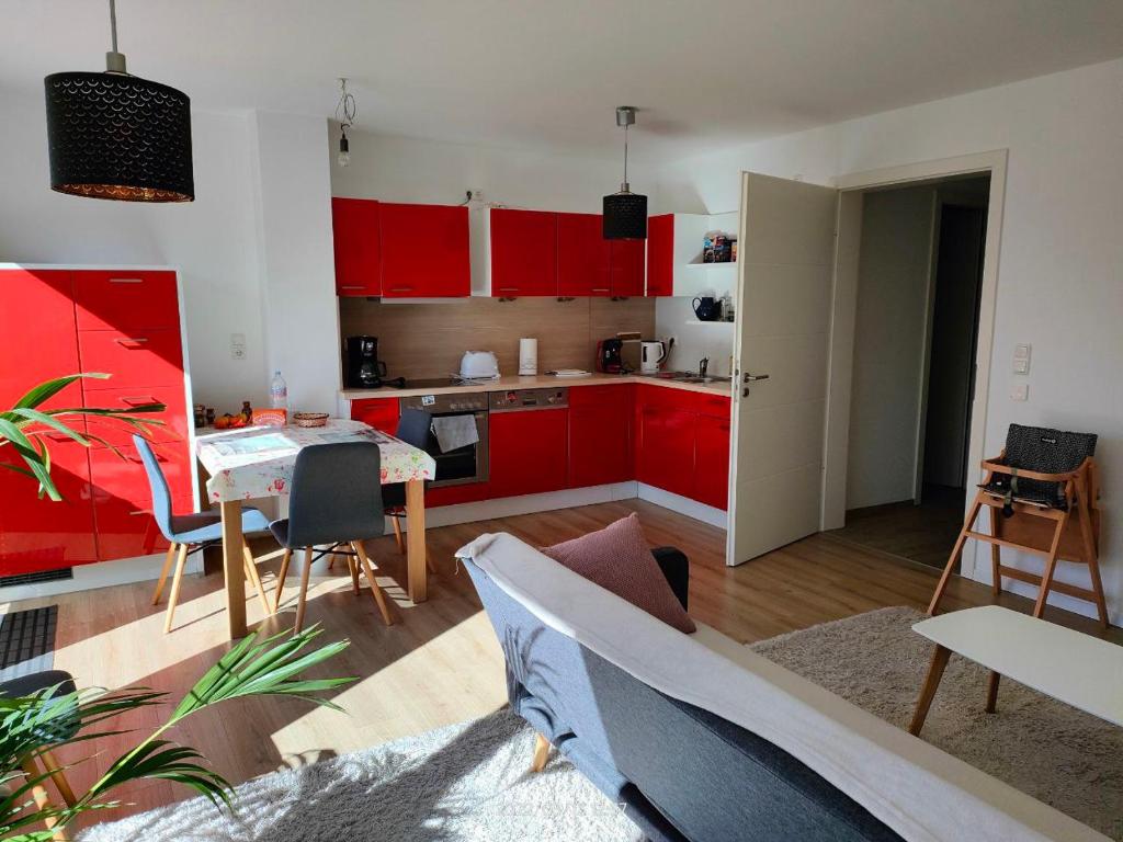 a kitchen with red cabinets and a table and chairs at Tolle Wohnung in Fontanestadt Neuruppin in Neuruppin