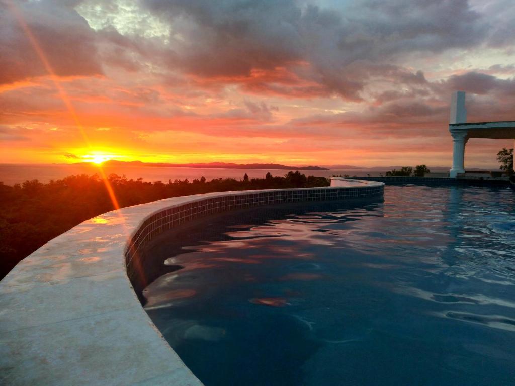 a infinity pool with a sunset in the background at Casa Blanca Inn in Torio