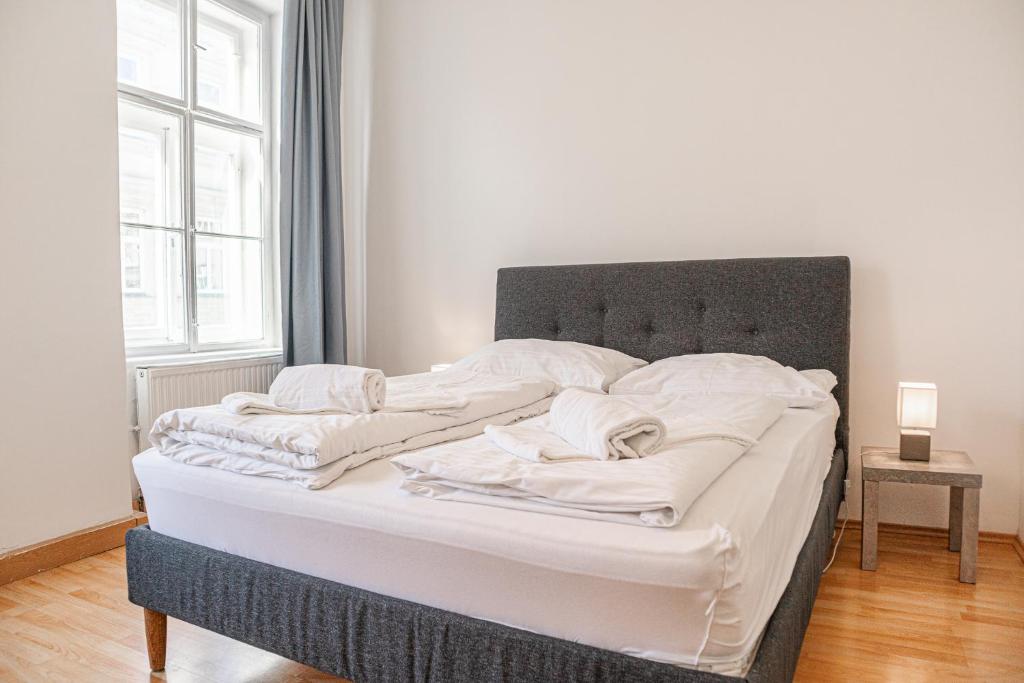 ein großes Bett mit weißer Bettwäsche und Kissen darauf in der Unterkunft Big Apt in Viennas Center - Perfect for Longstays in Wien