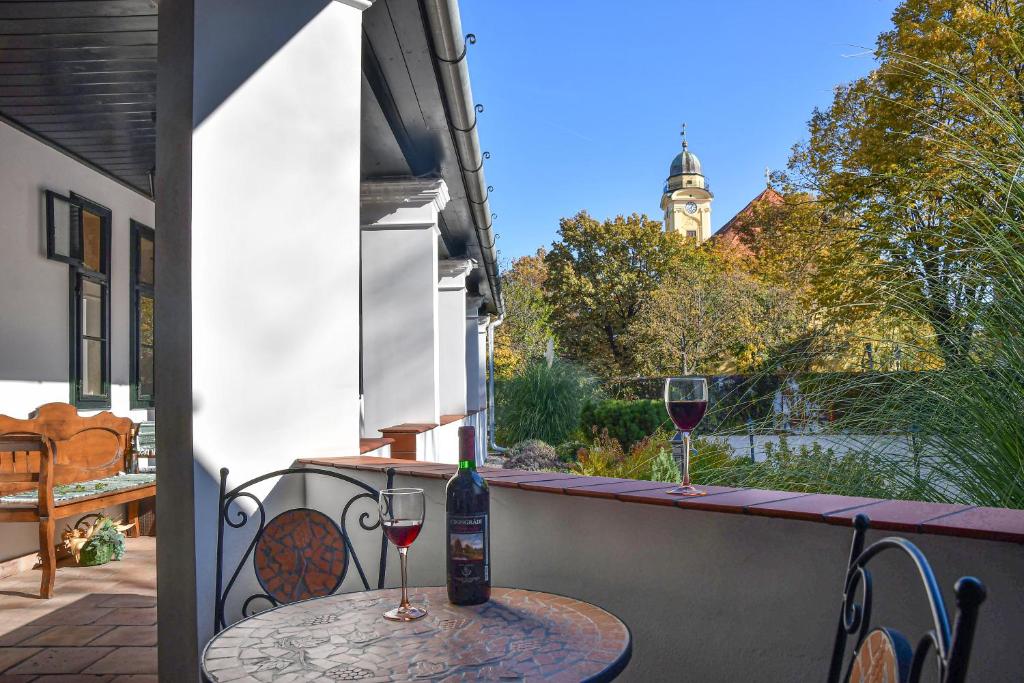 a table with two glasses of wine on a balcony at Szin-es Vendeghaz in Szentes