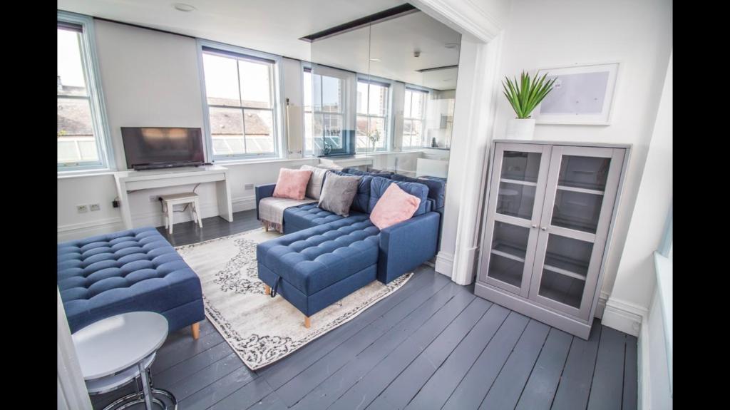 ein Wohnzimmer mit blauen Sofas und einem Tisch in der Unterkunft Luxury Penthouse in listed building in Newcastle upon Tyne