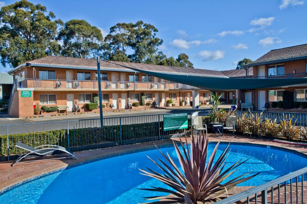 a hotel with a swimming pool in front of a building at Narellan Motor Inn in Narellan