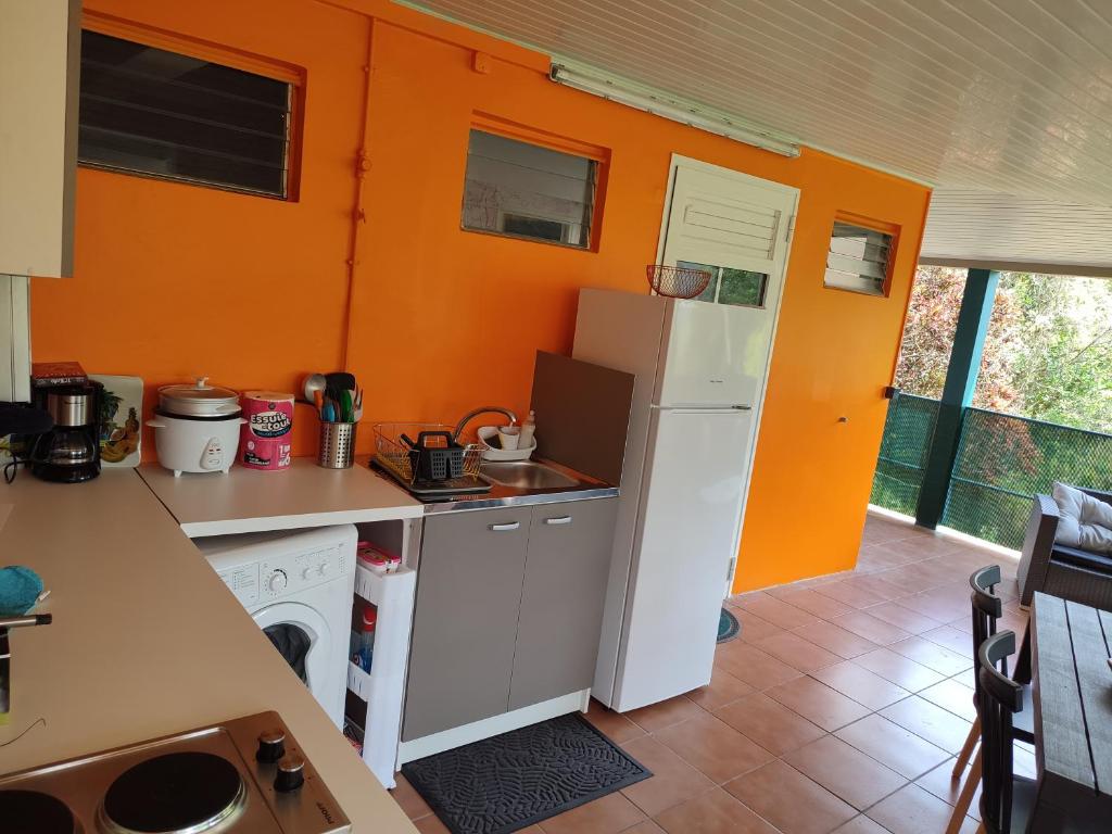 a kitchen with orange walls and a white refrigerator at Appartement Kelysa in Le Marin