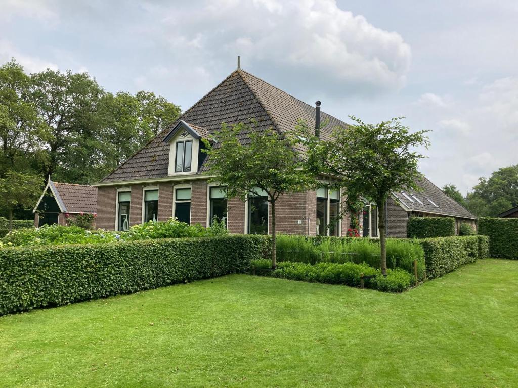 una casa con un seto delante de un patio en Duerswald, en Wijnjewoude
