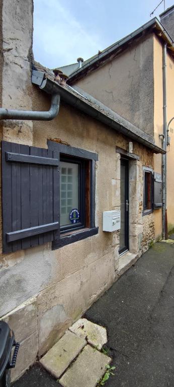 une maison avec une fenêtre et un volet dans l'établissement Chaleureuse petite maison de bourg, à Beaumont-sur-Sarthe