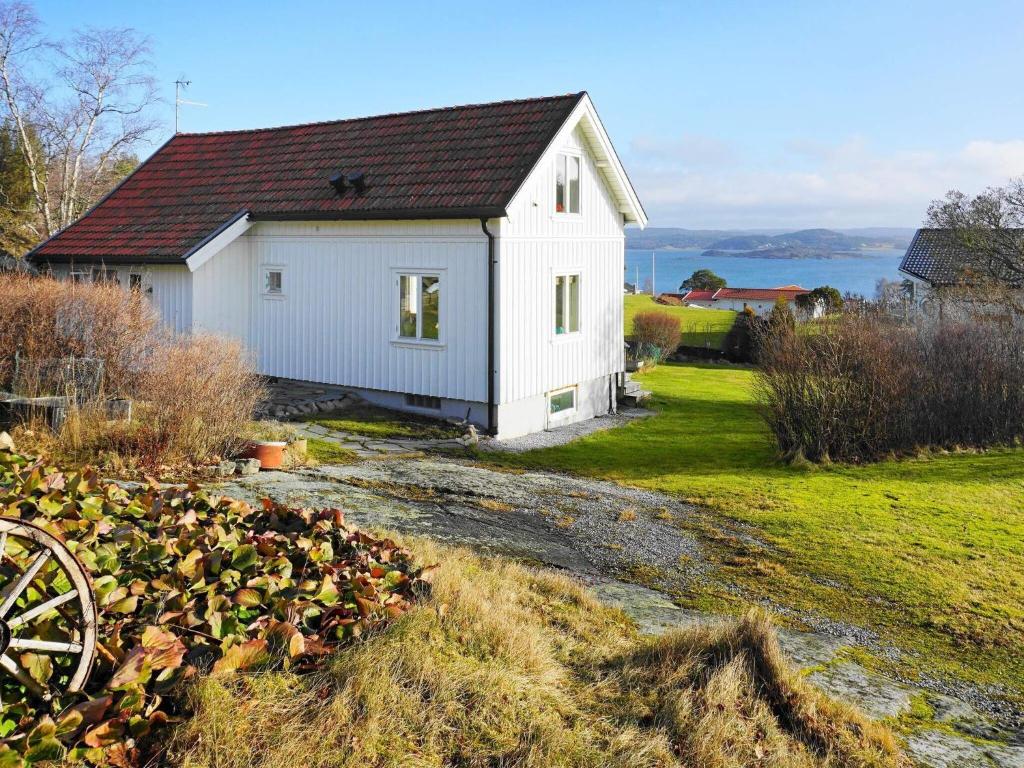 uma pequena casa branca com um campo e água em Holiday home Höviksnäs VI em Höviksnäs